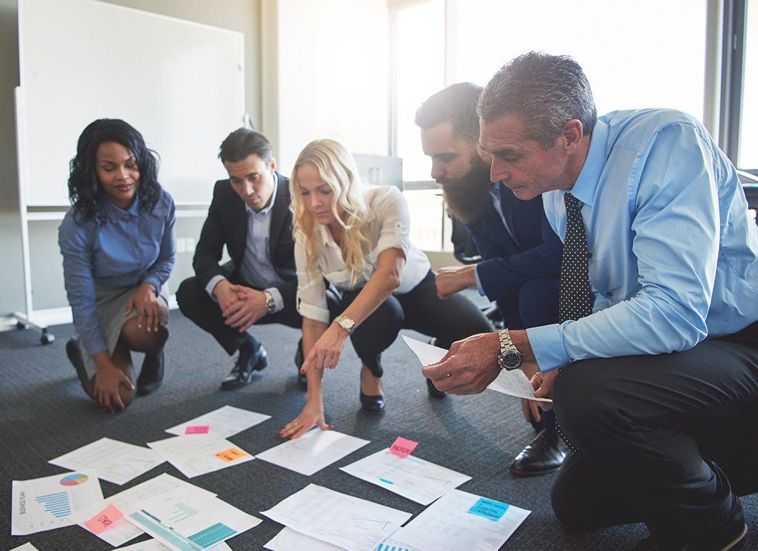 About Our Agency - Group of Business Professionals Kneeling Together While Working on Solving a Problem at an Office